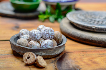 Old clay bowl with whole nutmegs close up, spices collection