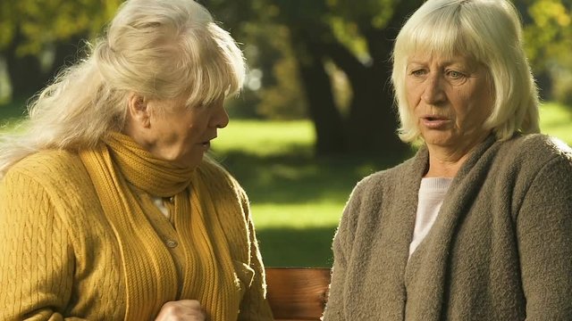 Elderly woman whispering rumor to friend, scandalous news shocks pensioners