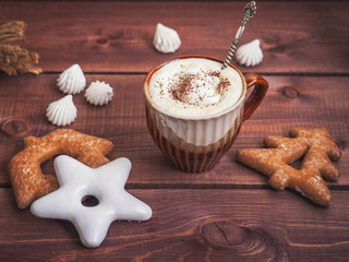 Coffee with whipped cream and chocolate. White, brown biscuit, bisa biscuit on a wooden tray. Vintage silver boat dropped into the cup.