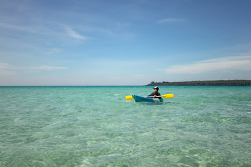 Asian boy in swimsuit rowing kayak at sea on sunshine day