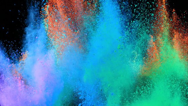 Super slowmotion shot of color powder explosions isolated on black background.