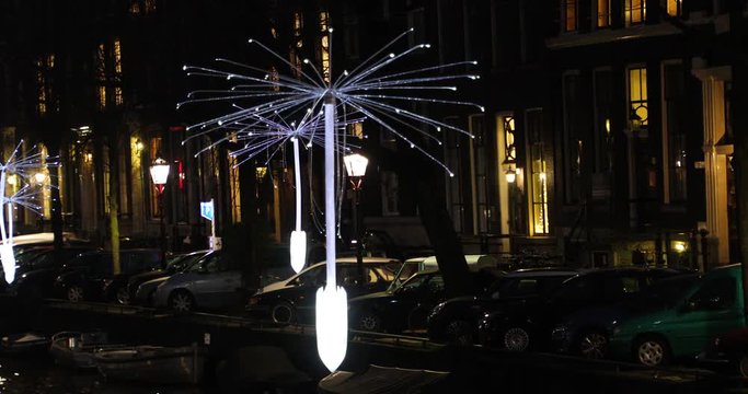 Light installation in the form of large dandelion seeds suspended above a canal, Amsterdam
