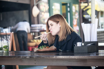 Girl eating in a street cafe