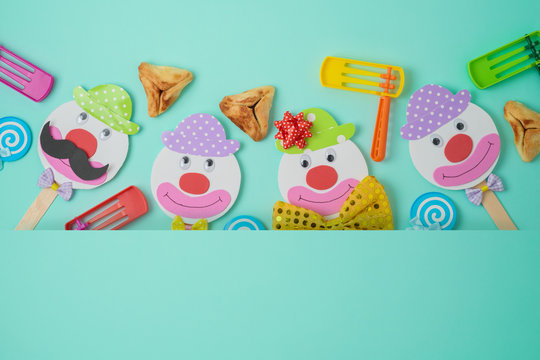 Jewish holiday Purim background with cute paper clowns characters and hamantaschen cookies.