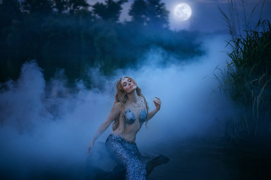 Neptune's daughter absorbs and eats moonlight, the magnificent sea ruler sits on a stone in the night river and rests in a thick fog, a fabulous character with art processing photos