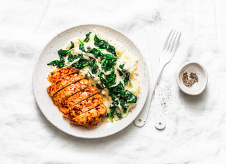 Baked chicken breast, mashed potatoes with creamy spinach on a light background, top view. Comfort...