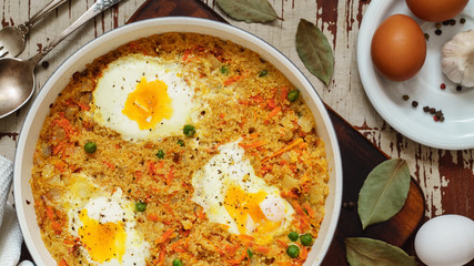 Wheat porridge with vegetables and eggs in a white pan