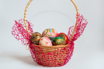 Colorful decorated and painted Easter eggs in wooden basket isolated on white background. Easter holiday concept.