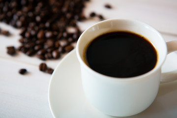 cup of coffee and beans on white wooden background