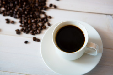 cup of coffee and beans on white wooden background