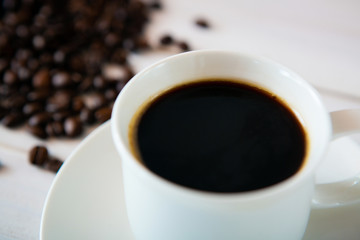 Fototapeta premium cup of coffee and beans on white wooden background