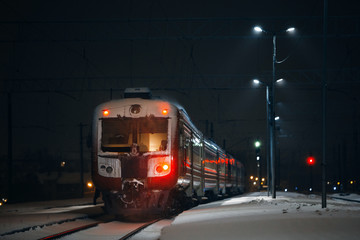 Train on railroad station during snowing at night. Train at the empty station during a night at...