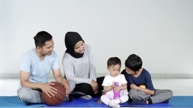 Happy Asian family taking a rest after workout while talking and sitting on the exercise mat. Shot in 4k resolution