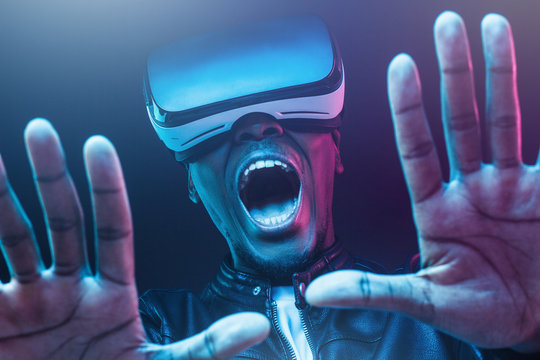 Close-up headshot of excited young african man enjoying virtual reality with mouth wide open