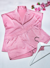 women's silk pink pajamas with a coat hanger on a white background