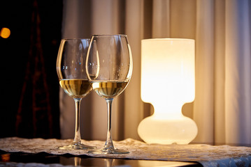 Glass white wine on the table with a burning lamp in a cozy restaurant.