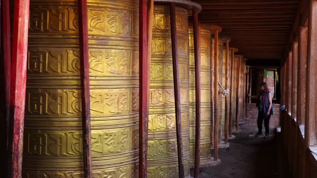 European hiker woman turning the prayer wheels, Eastern Tibet, China