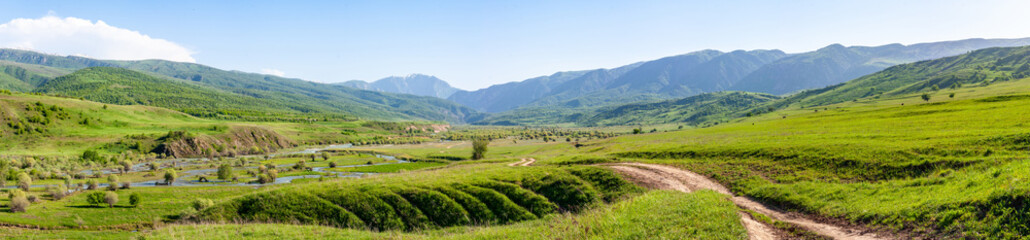 Naklejka na ściany i meble Panorama of a wide mountain valley on a sunny day