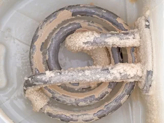 Sierkussen Kalkaanslag in oude ketel, behaard element. Een wit, krijtachtig residu van afzetting van calciumcarbonaat. Hard water probleem. © Mushy