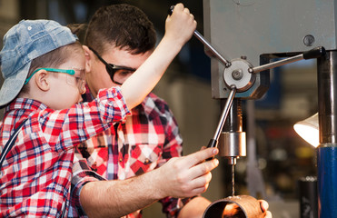 good father took his little son to work with metal. Concept of relationship, child at work turner