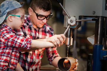 good father took his little son to work with metal. Concept of relationship, child at work turner