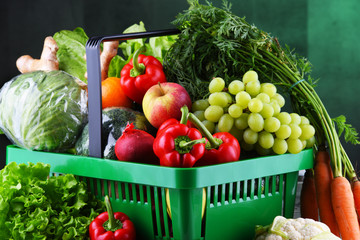 Fresh organic fruits and vegetables in plastic shopping basket