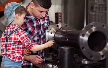 good father took his little son to work with metal. Concept of relationship, child at work turner