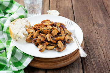 Fried mushrooms with fresh herbs in white plate .