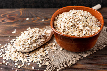 Rolled oats in bowl on dark wooden background.