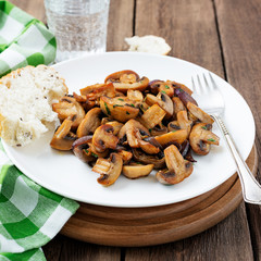 Fried mushrooms with fresh herbs in white plate .