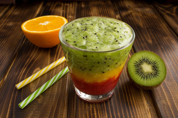 Colorful smoothies with kiwi,orange and strawberry on the brown wooden background