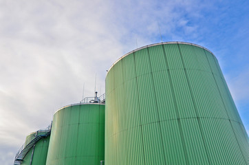 Three biogas tanks on a biogas station. Wastes recycling ecology concept. Green economics. Copy space. Blue sky background. - obrazy, fototapety, plakaty