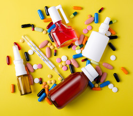 Pills capsules thermometer nose throat spray cough syrup medicine health on yellow background top...