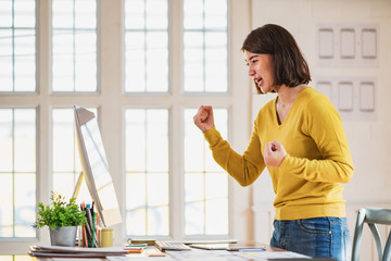 Beautiful Asian girl celebrate with laptop in office.