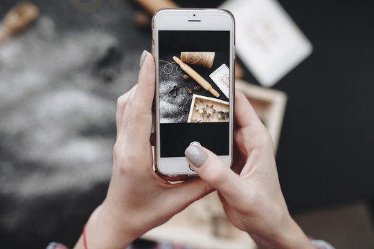 Hands Of Woman Holding Phone In Kitchen Above Table