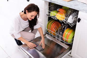 Woman Putting Soap Tablet In Dishwasher Box