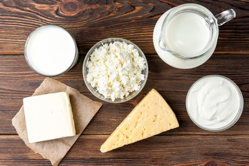 Dairy products on dark wooden background. Milk, kefir, cheese, cottage cheese, butter and sour cream.
