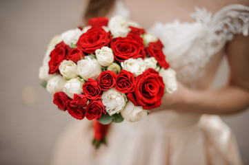 Elegant bride in a wedding dress holding a bouquet of white and red roses