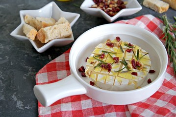Baked camembert or brie with rosemary, garlic and olive oil. Served with dried cranberries, walnuts and white bread croutons.