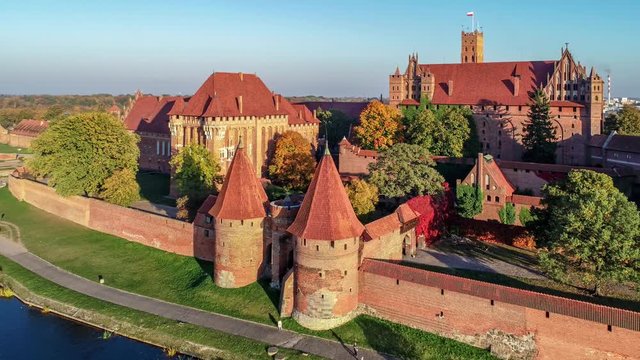 Medieval Malbork (Marienburg) Castle in Poland, main fortress of the Teutonic Knights at the Nogat river. Aerial revealing 4K video in sunset light