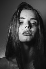 Black and white dramatic portrait of a beautiful girl with long hair and freckles