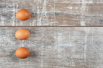 Three eggs in a vertical row on wooden background