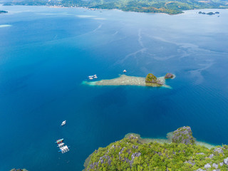 Fototapeta na wymiar Aerial view to tropical lagoon with azure water and traditional sailing boat near Barracuda Lake, Coron island. Palawan, Philippines.