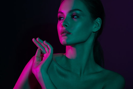 Young beautiful girl with purple and green neon lighting