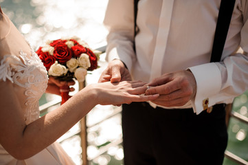 Obraz na płótnie Canvas Broom putting on a golden wedding ring to a tender bride finger