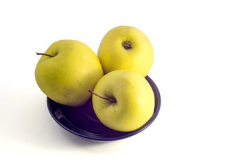  Yellow apples in a dark blue plate on a white background