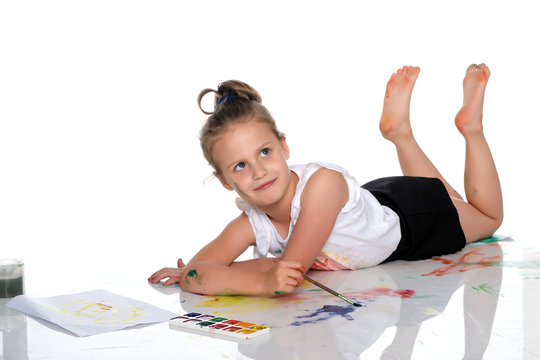 A little girl paints with paint and brush.