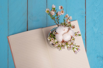 Vase of flowers and open notebook on wooden table