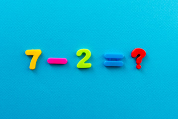 math action from colored plastic numbers on blue paper background