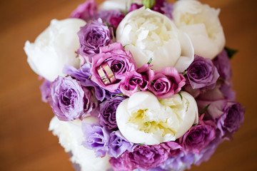 A pair of wedding gold rings on a bouquet of colorful flowers, close up shot